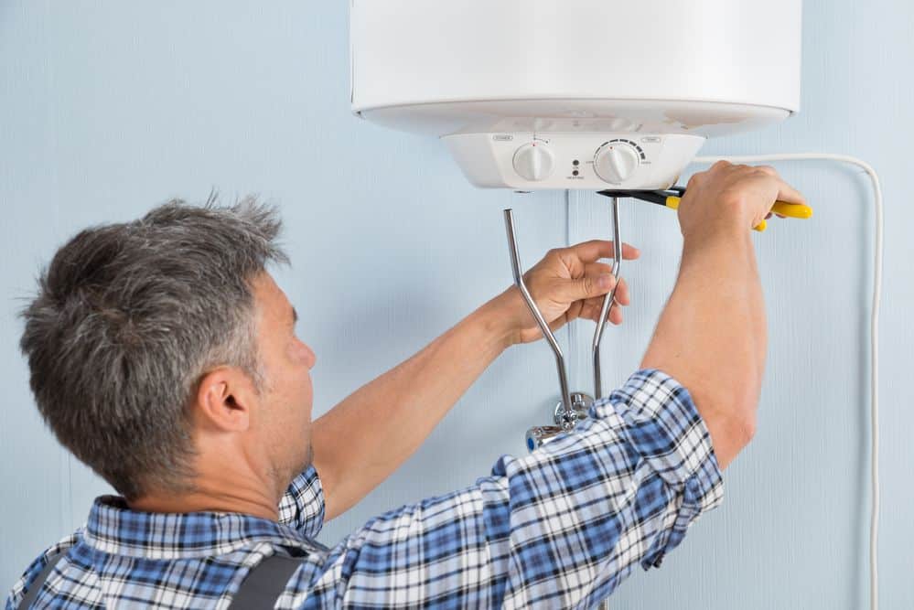 A man working on the top of a water heater.